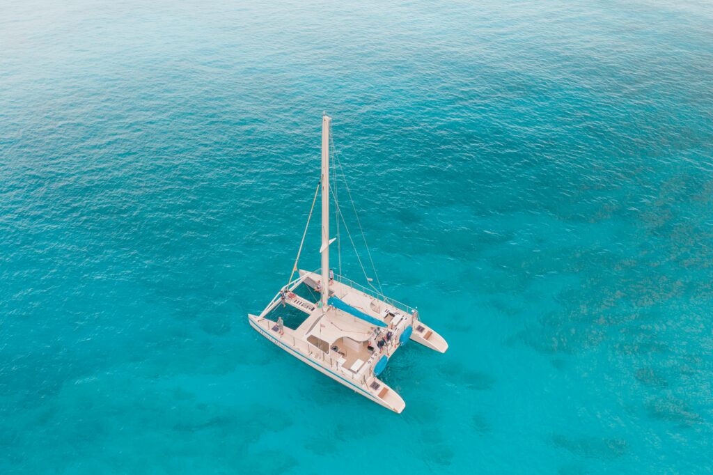 Stunning aerial view of a catamaran sailing in crystal clear turquoise waters.